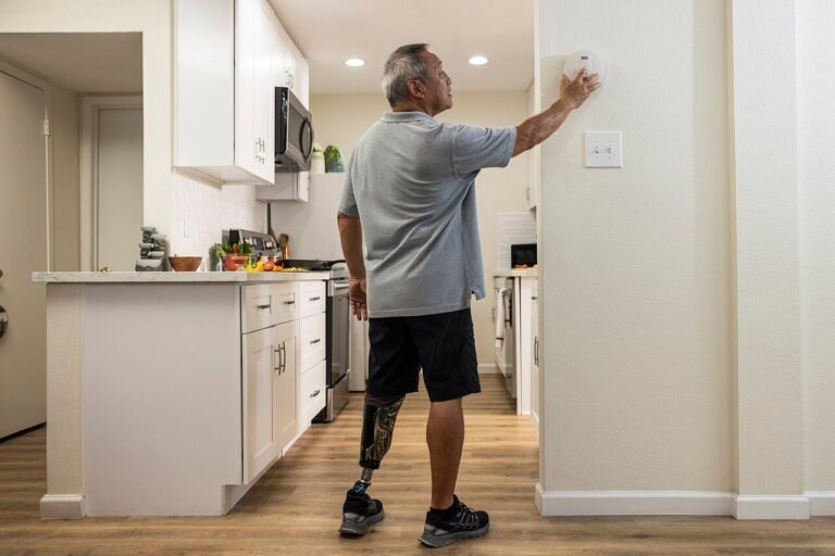 Fire Safety - Person with a prosthetic leg testing their smoke alarm.jpg