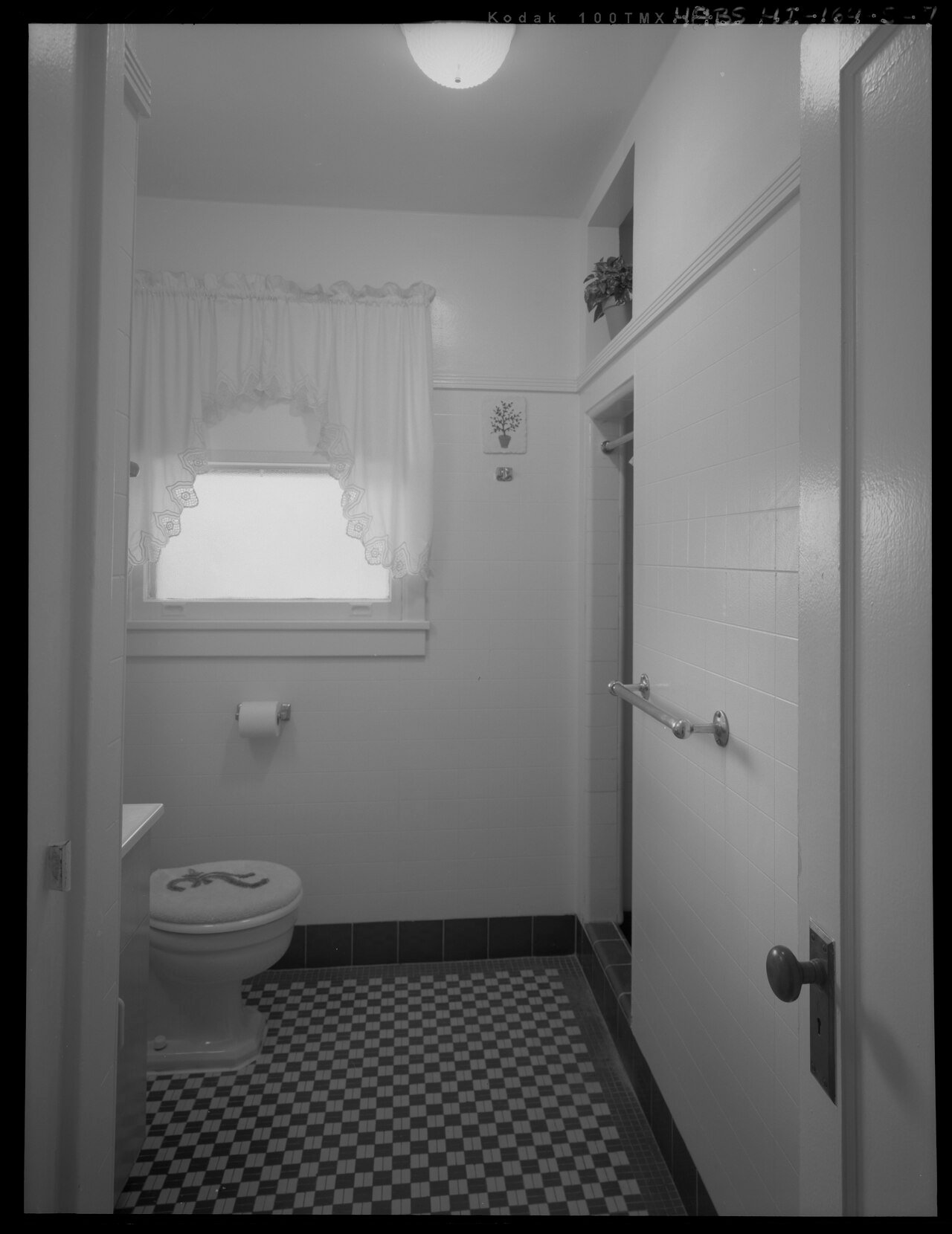 INTERIOR VIEW OF BATHROOM 1. NOTE THE ORIGINAL MOSAIC PATTERN FLOOR TILE, ASBESTOS CEMENT WALL BOARD, AND OPEN TRANSOM OVER THE SHOWER DOORWAY. VIEW FACING WEST. - Hickam Field, HABS HI-164-S-7.tif