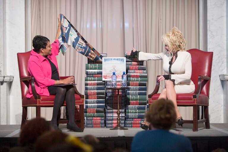 Librarian of Congress Carla Hayden (left) and Dolly Parton unveil “Coat of Many Colors,” the book Parton donated to the Library this week.jpg